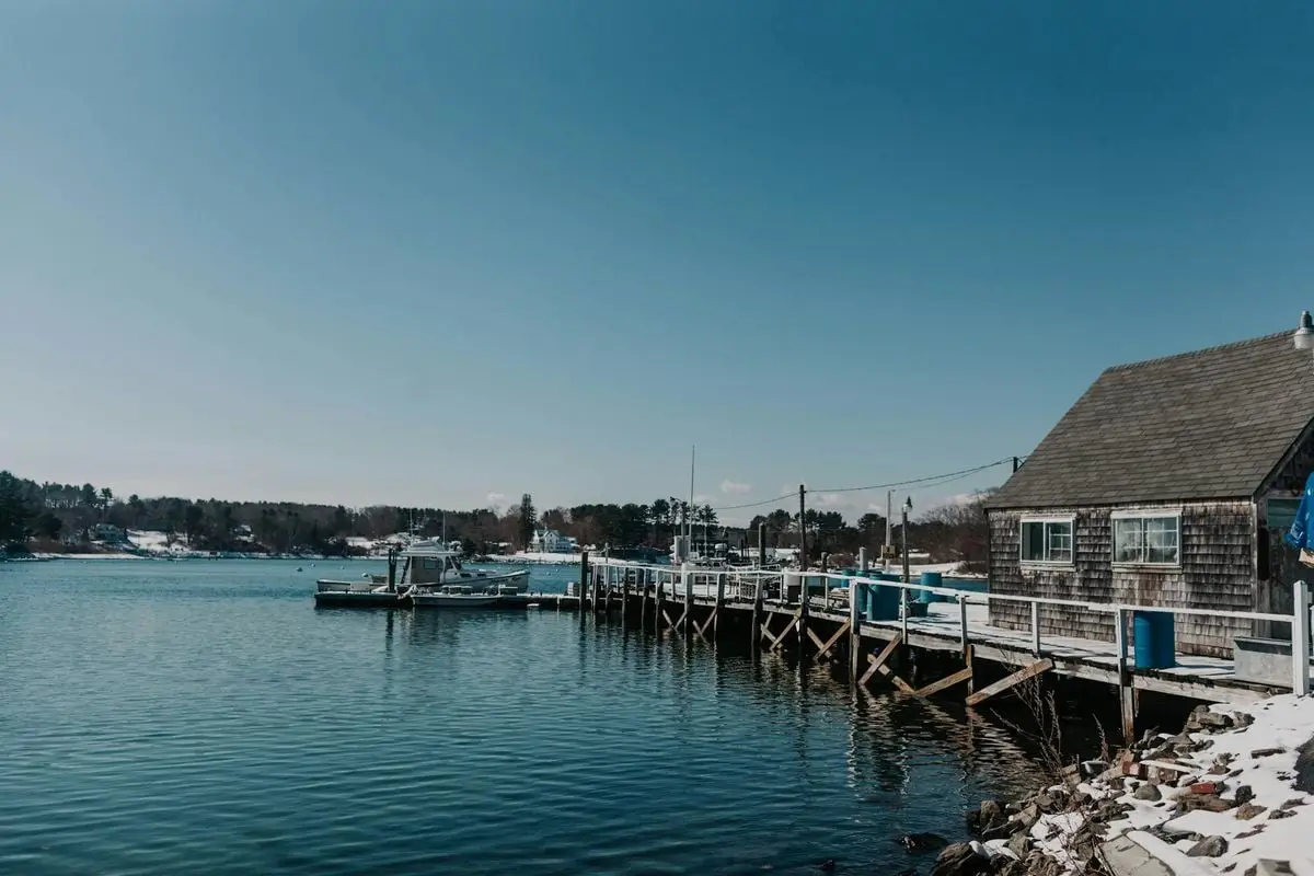 A tranquil winter scene of a dock and snowy shoreline in York, Maine.