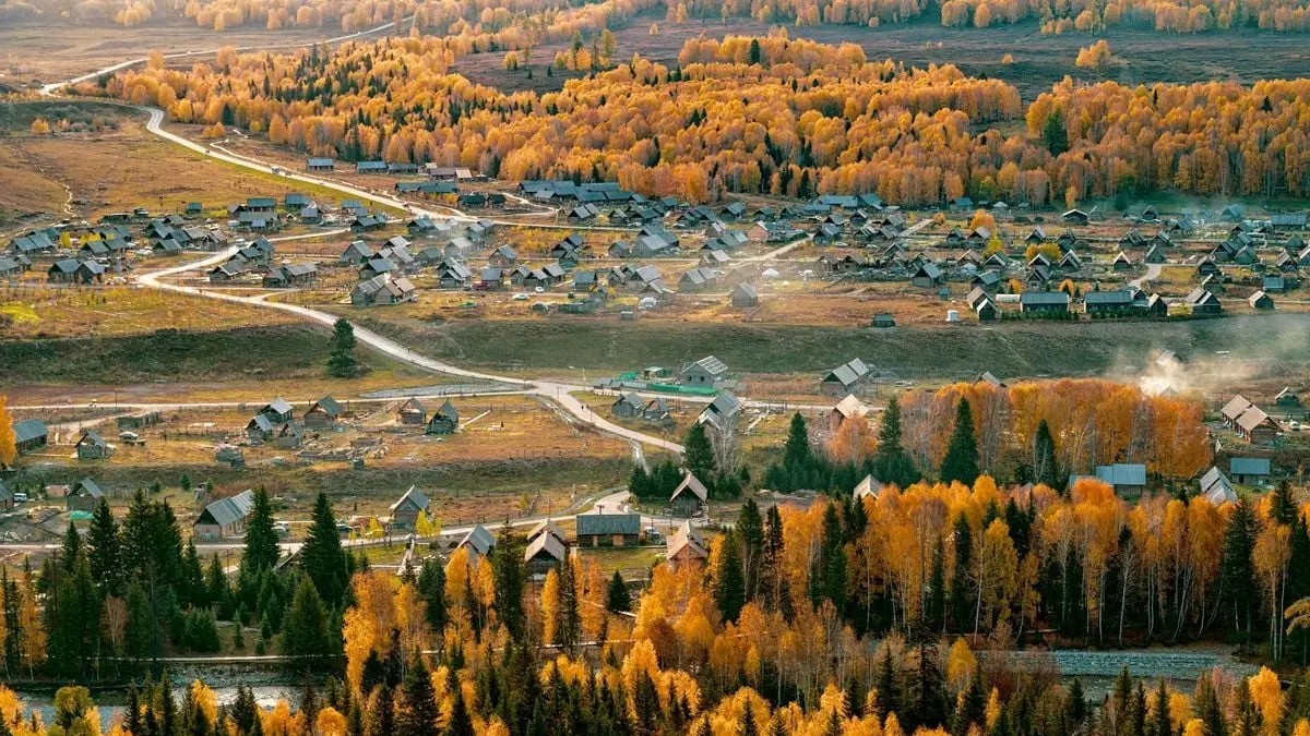A picturesque aerial view of a village surrounded by vibrant autumn foliage.