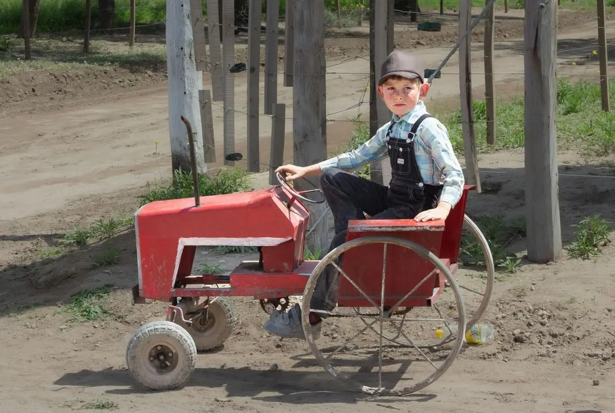 A young boy on a vintage toy tractor in rural Guatraché, Argentina. Sunny outdoor scene.