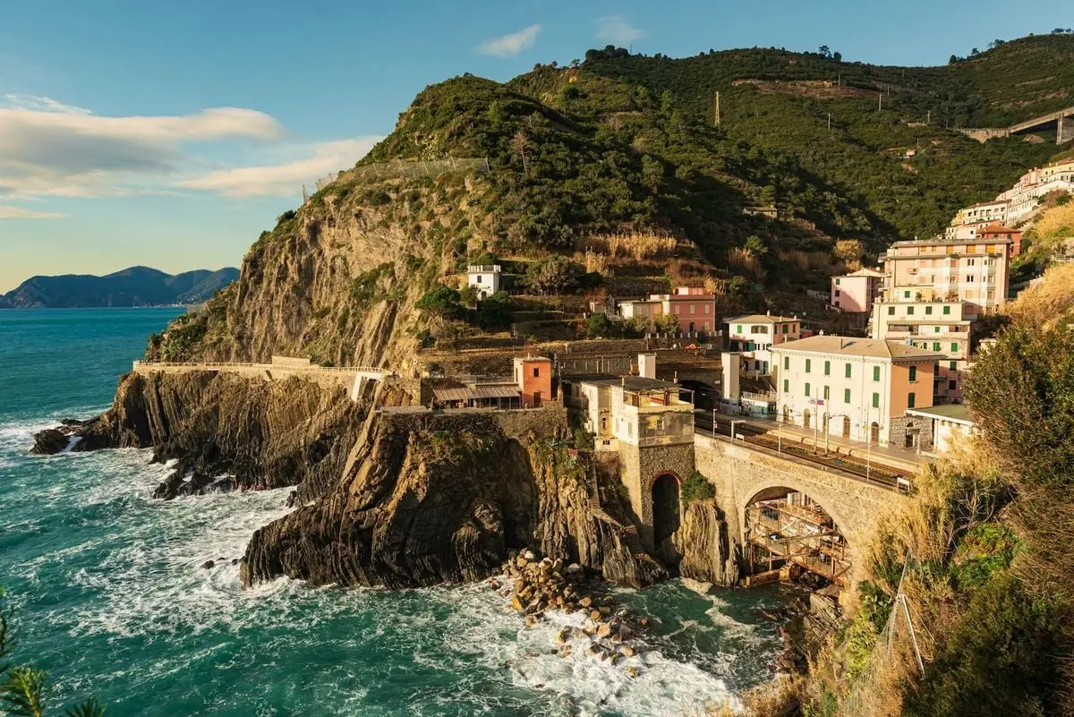 Breathtaking view of Riomaggiore village with cliffside buildings and azure sea in Liguria, Italy.