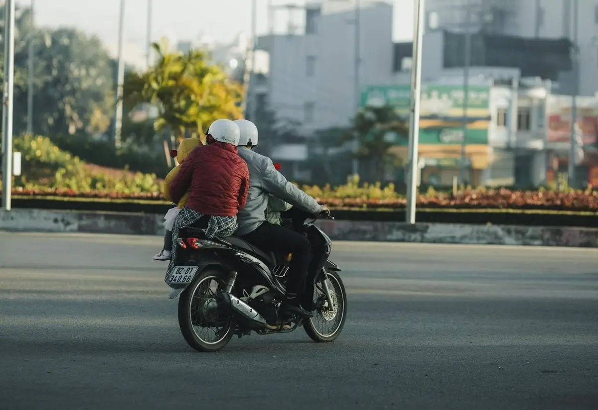 A family riding a motorbike in Kon Tum, Vietnam, on a sunny day.