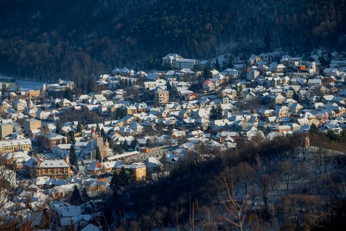 Charming European village blanketed in snow with a mountain backdrop, captured during winter.