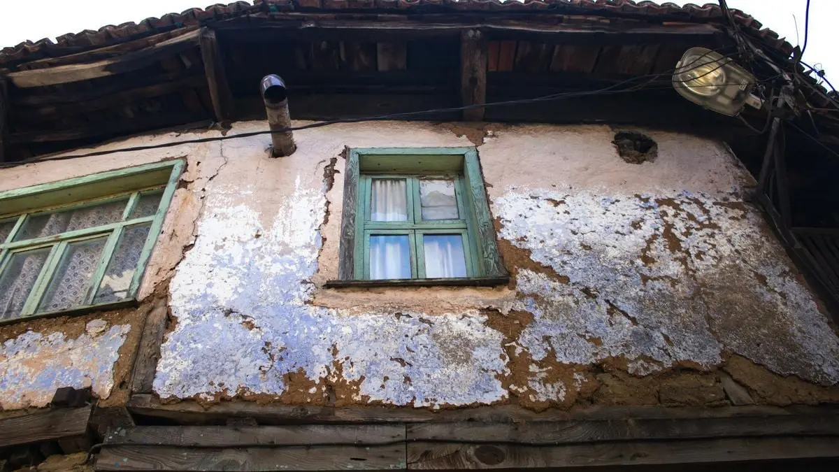 A weathered and dilapidated wooden house with distinct windows in Bursa, Türkiye.