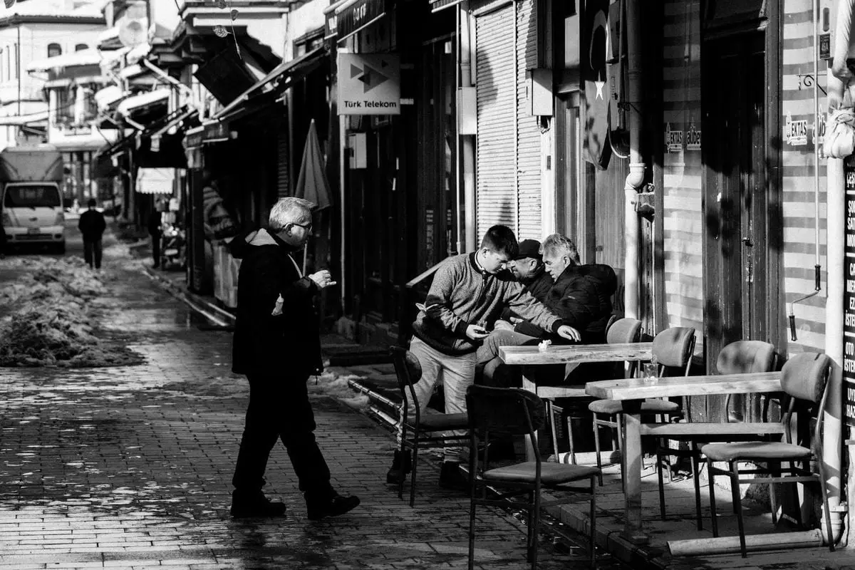 Charming black and white photo of daily life in Mudurnu, Türkiye featuring people in an alleyway.