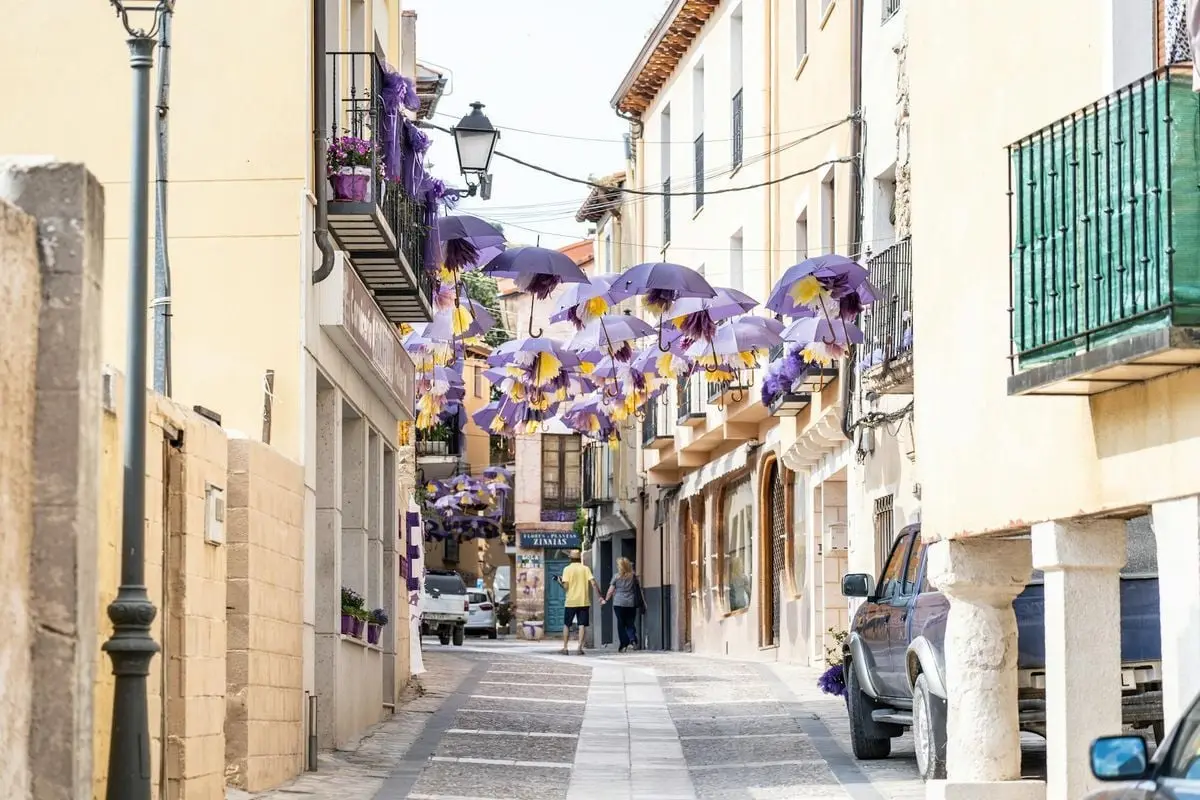 An enchanting street scene with vibrant purple umbrellas hanging overhead.