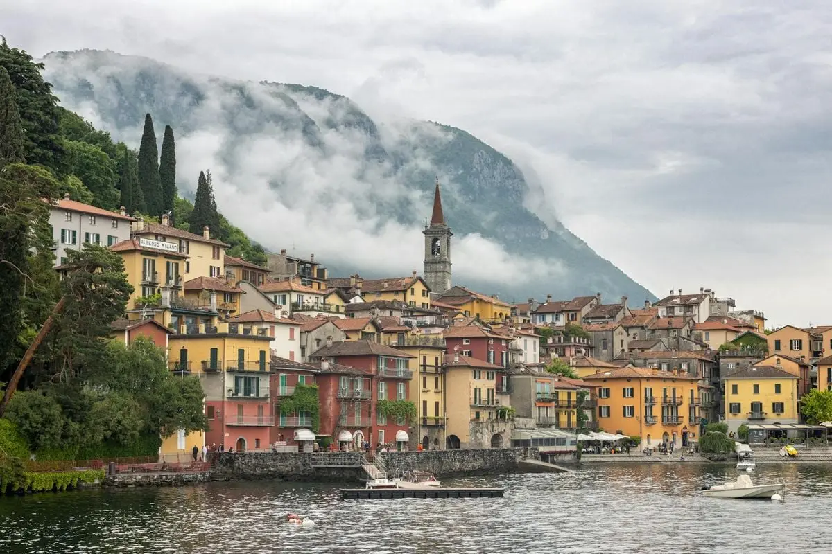 Scenic view of Varenna, Italy with colorful buildings and misty mountains by Lake Como.