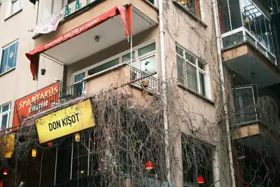 Low angle shot of an urban building with ivy-clad balconies and vibrant signs in a Turkish town.