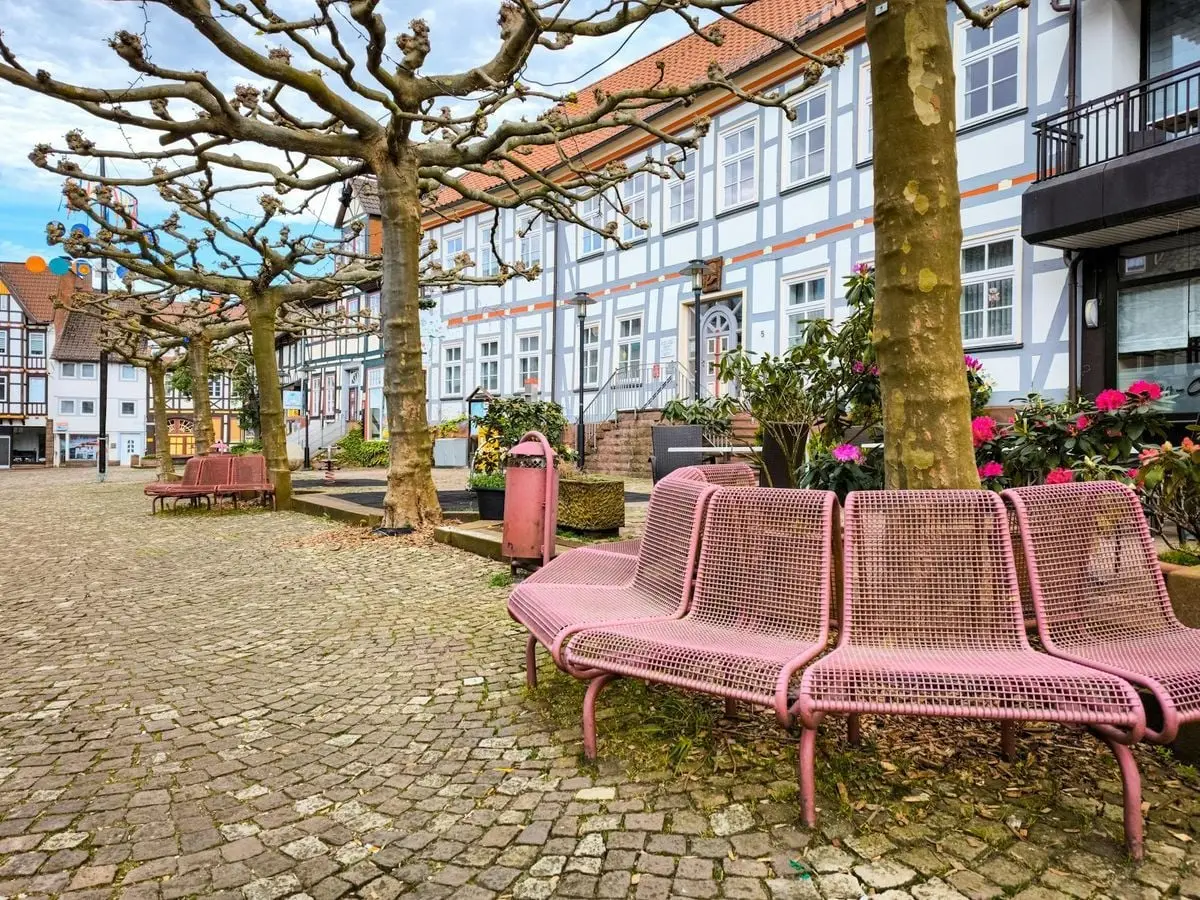 Cobblestone square with pink benches and historic European architecture in a quaint old town setting.