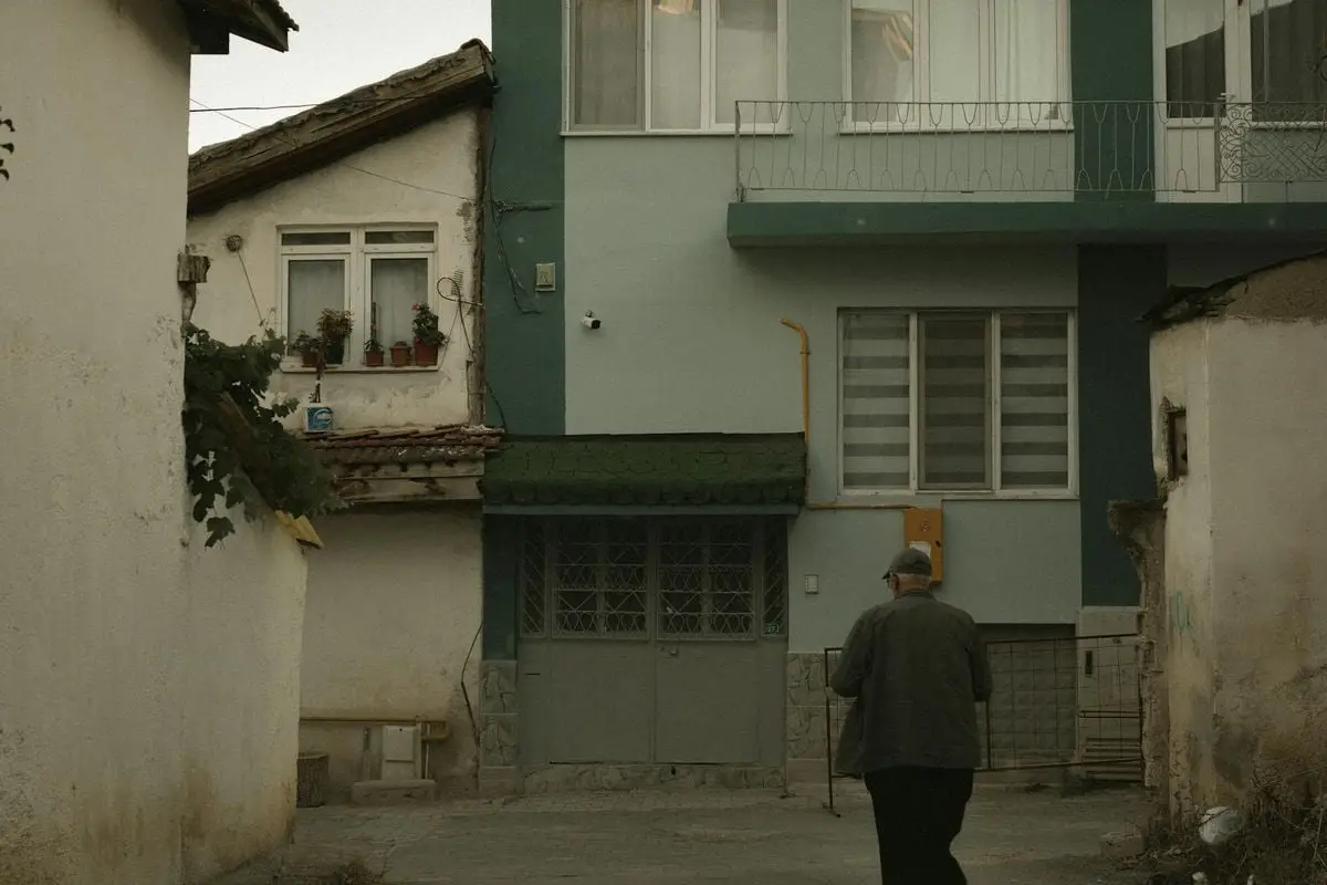 An elderly man walks in a quaint street of Merzifon, showcasing traditional architecture.