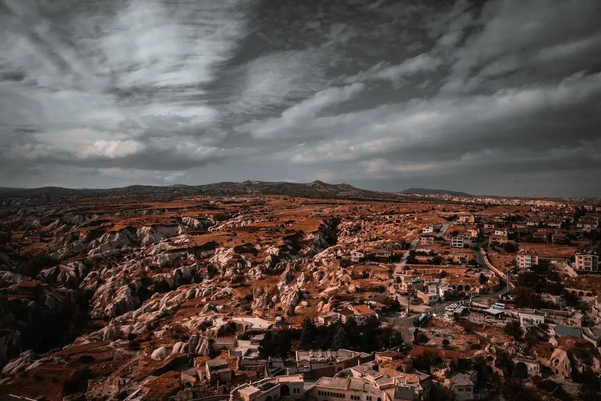 Dramatic aerial view of a rocky landscape and small town under cloudy skies.