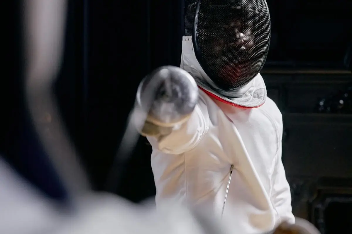 Close-up of a fencer in action, ready to strike during an indoor competition.