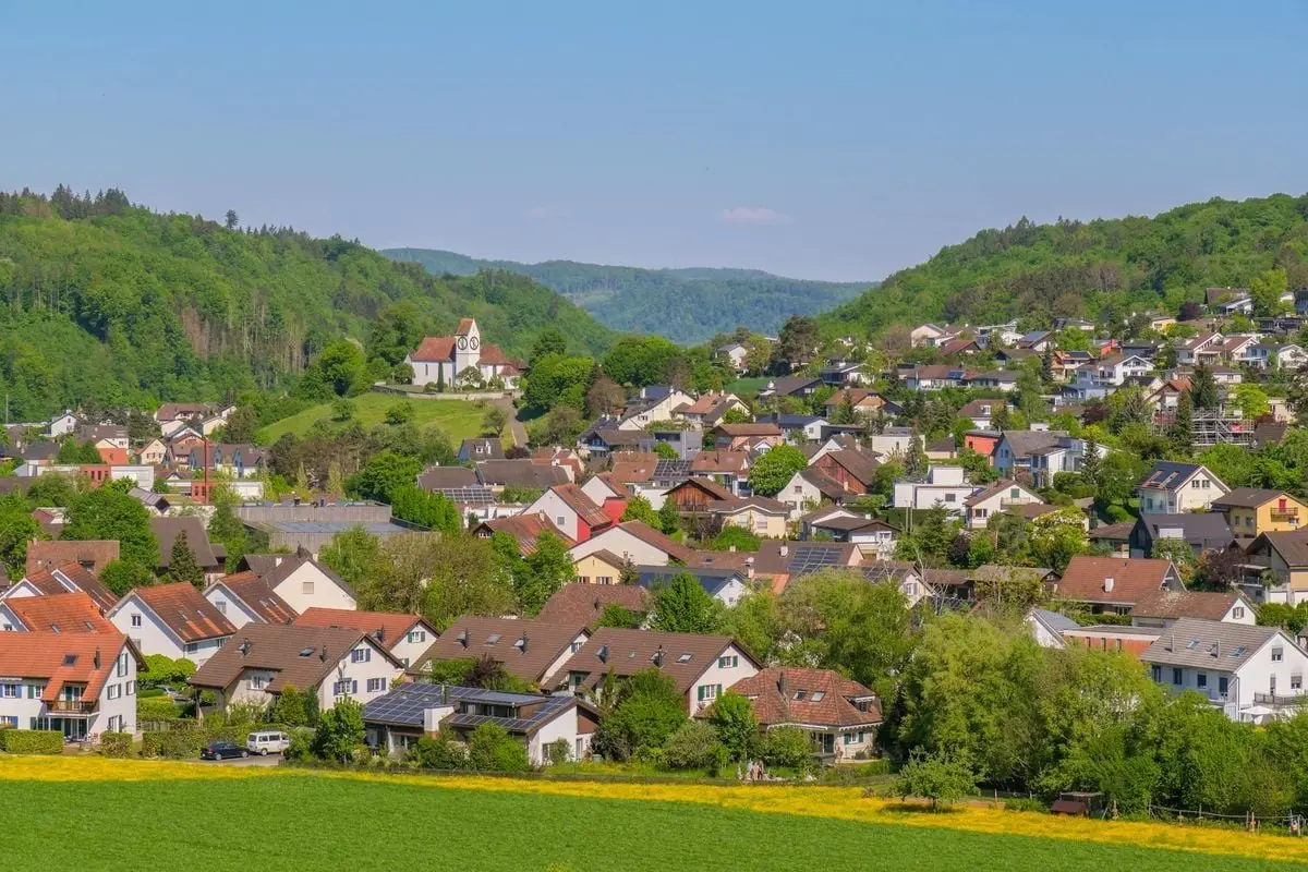 A picturesque village nestled among lush green hills under a clear blue sky.
