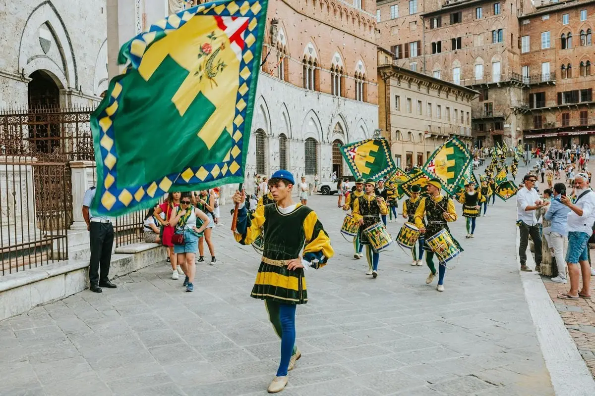 Traditional flag bearers in a colorful parade in Piazza del Campo, Siena, showcasing rich Italian heritage.