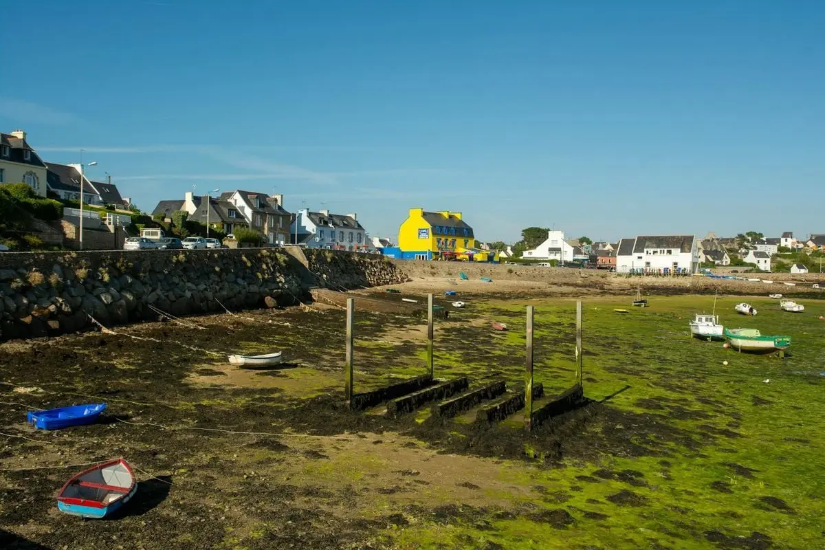 Charming seaside village in Bretagne during low tide, showcasing colorful architecture and boats.