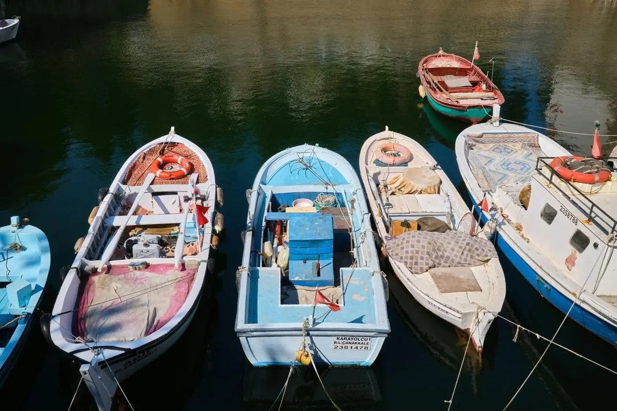 Row of vibrant fishing boats moored in Çanakkale, Turkey on a sunny day.