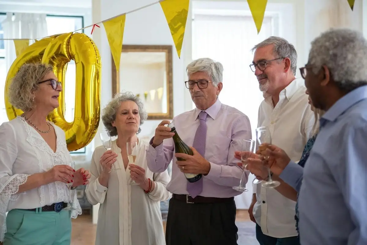 A group of senior friends celebrating with champagne indoors, showcasing joy and companionship.