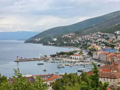 Picturesque coastal harbor with boats and hillside town in Croatia.