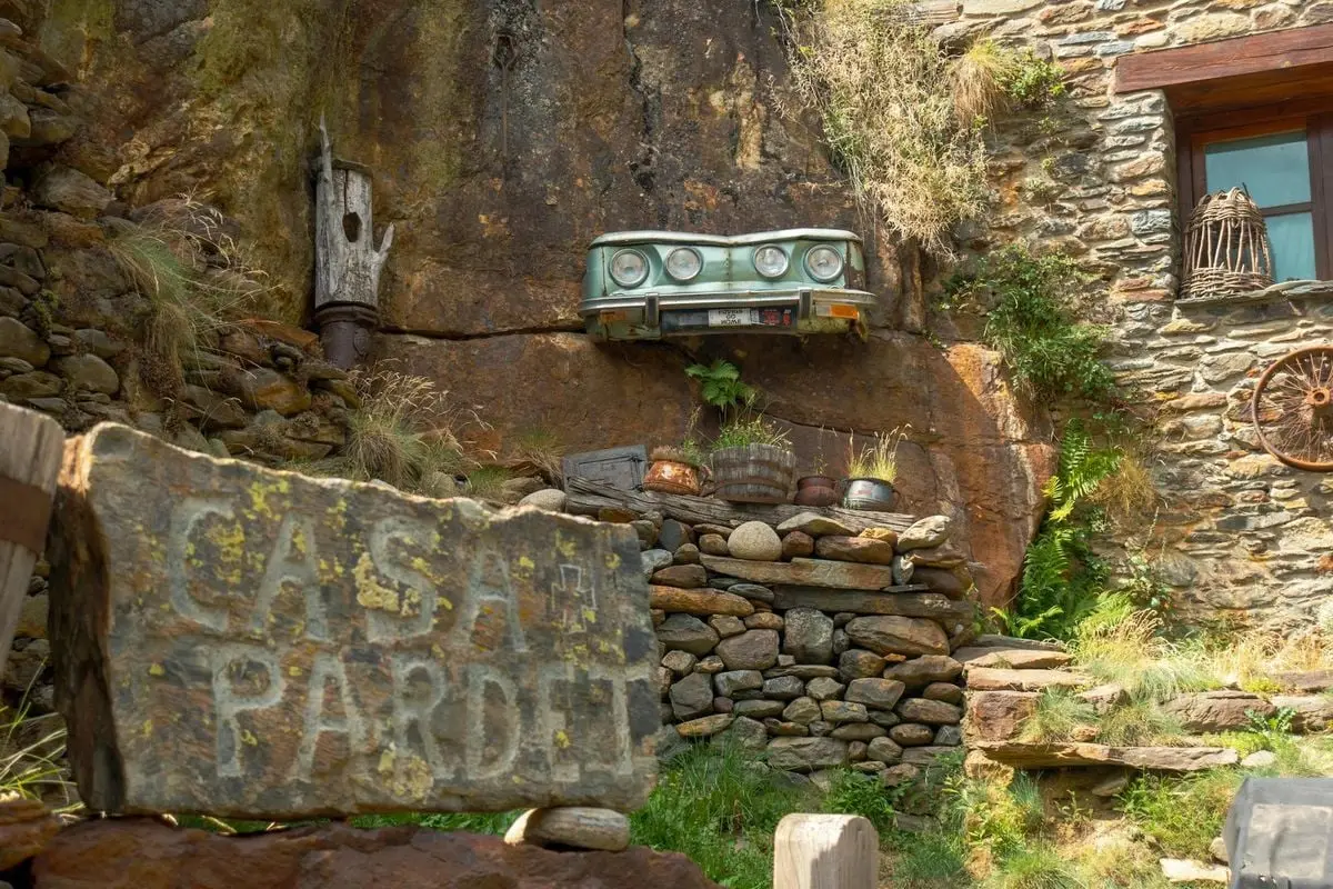 Charming rustic stone house in Tavascan, Spain, featuring vintage car decor and lush greenery.