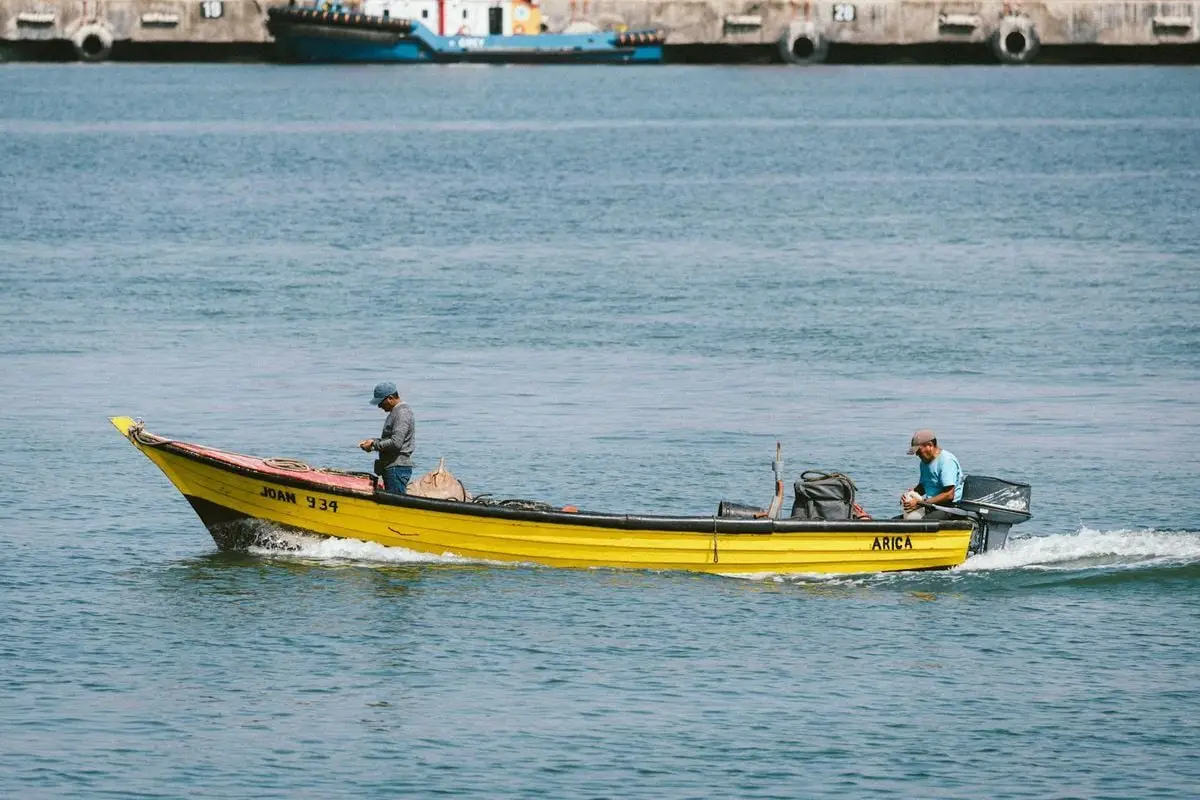 Fishermen on a yellow boat navigating the coastal waters of Arica, Chile on a sunny day.