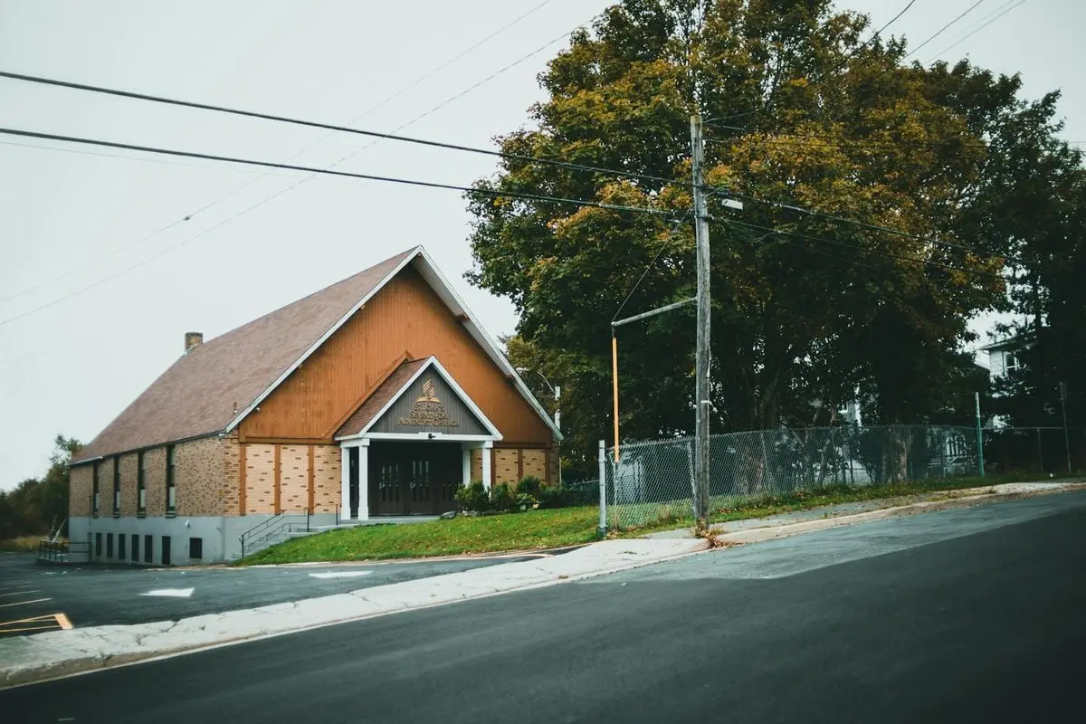 Charming rural church by a quiet road, surrounded by lush autumn foliage, providing a serene and picturesque setting.