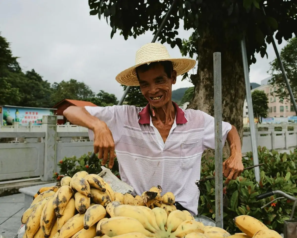 Friendly street vendor with bananas in an urban setting, exuding joy.