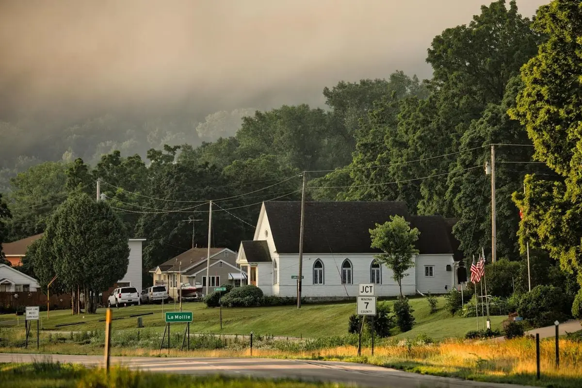 A foggy morning scene in Dakota, MN showcasing a quaint small town with green trees and classic architecture.