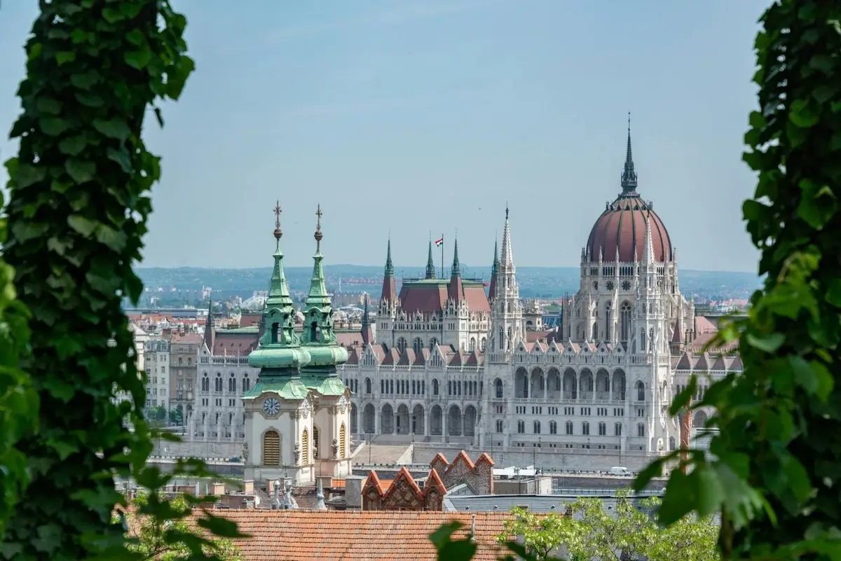 Captivating view of Budapest's iconic Parliament framed by lush greenery.