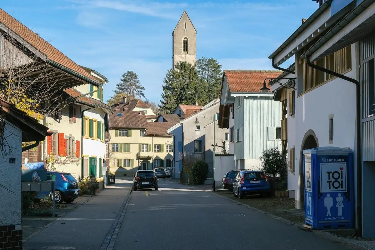 Picturesque view of a quaint European village street with traditional buildings and a church tower.