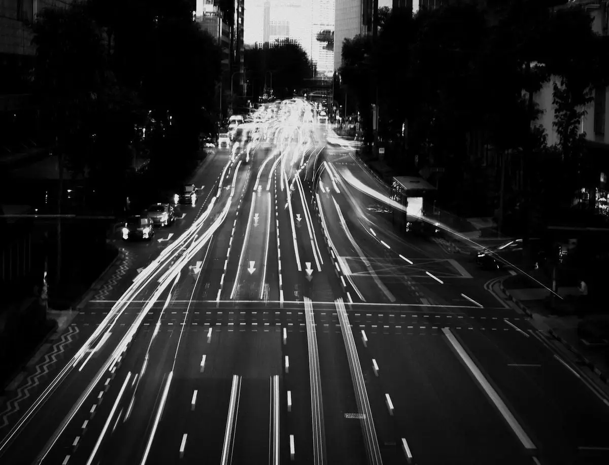 Long exposure black and white shot capturing city traffic lights at night, emphasizing motion and urban energy.
