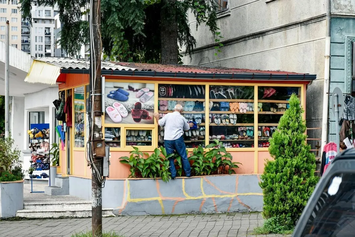 A man inspects colorful footwear at a vibrant street vendor booth.
