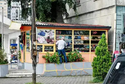 A man inspects colorful footwear at a vibrant street vendor booth.