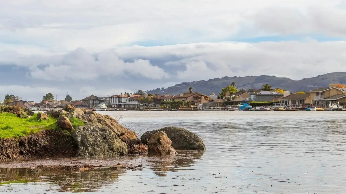 River view of houses with scenic rocks and overcast skies, ideal for travel and nature themes.