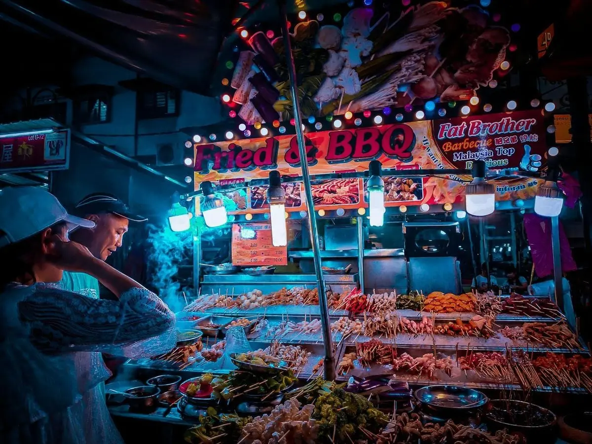 Explore the lively street food scene at a vibrant BBQ stall in Kuala Lumpur's night market.