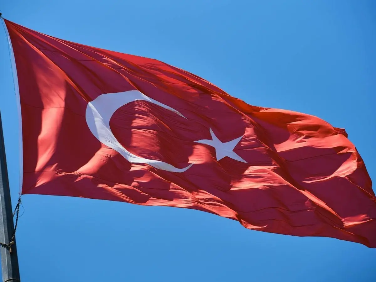 The Turkish flag majestically waves against a bright blue sky, symbolizing national pride.