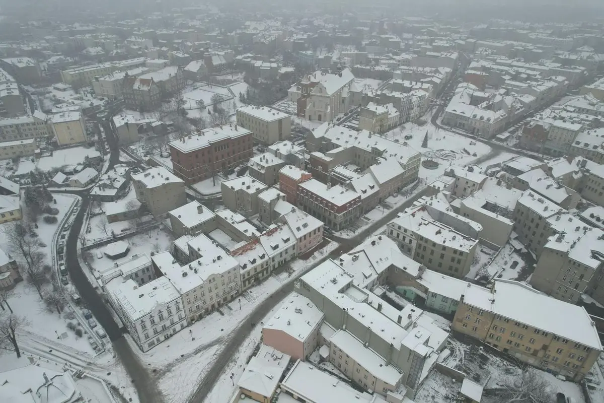 Aerial winter view of a snow-covered town with historic buildings and roads.