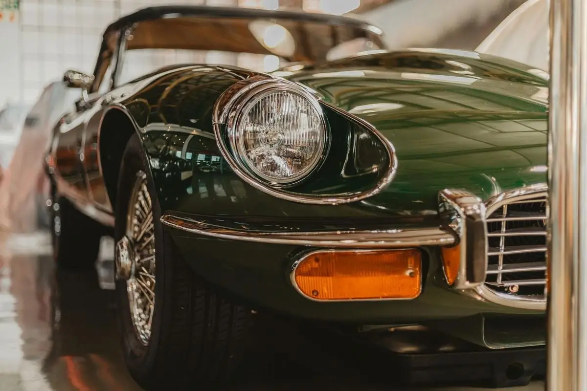 Close-up of a classic green vintage car on display in Cape Town, highlighting a shiny bumper and headlight.