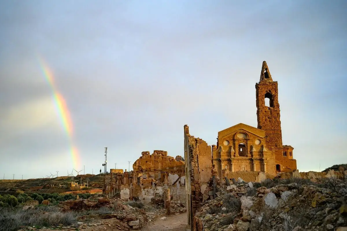 Scenic view of Belchite's historic ruins with a rainbow arching over the landscape.