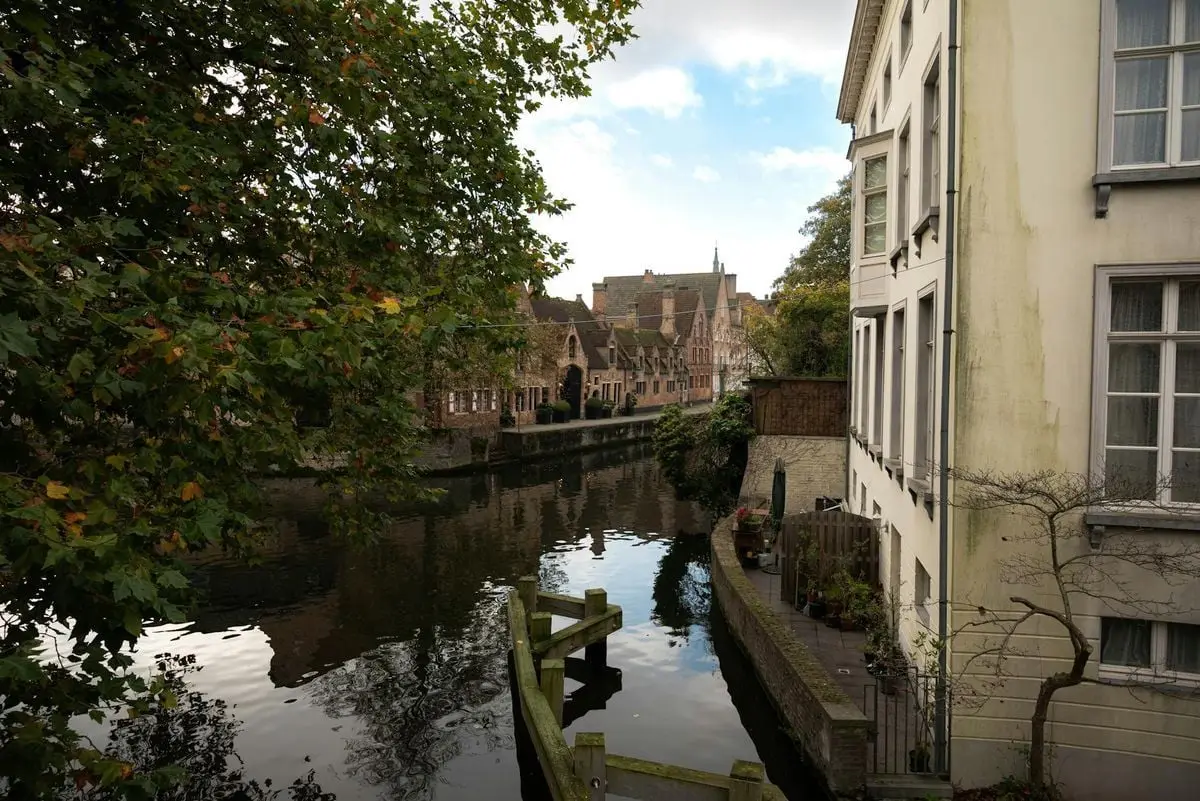 Picturesque canal and historic buildings in Bruges, Belgium with reflections of autumn scenery.