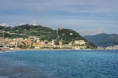 Picturesque view of Noli's coastline in Liguria, Italy, featuring historical castle and lush hills.