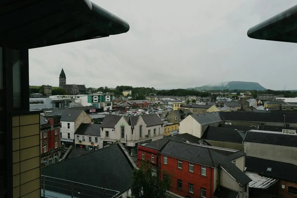 An aerial view of Sligo, featuring a historic church, colorful buildings, and a distant mountain under an overcast sky.