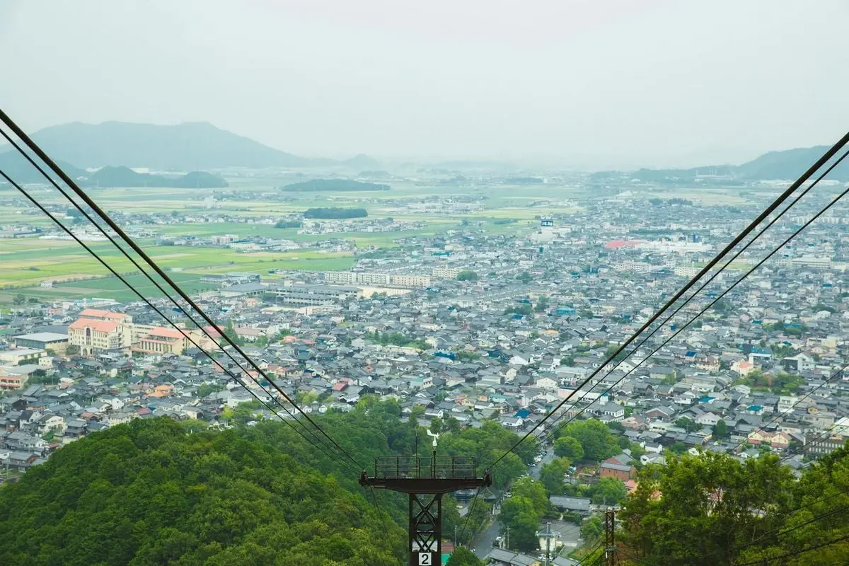 Picturesque scenery of rope way cable against contemporary city situated on vast hilly valley on clear day