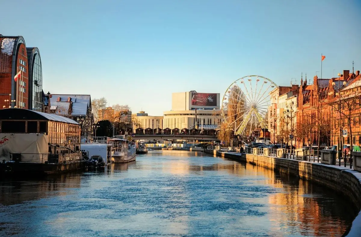 Explore the picturesque winter scene of Bydgoszcz canal with ferris wheel and city's Opera Nova in Poland.