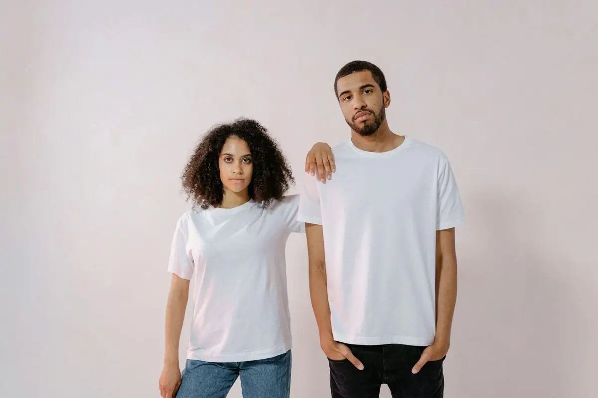 A young man and woman in casual white T-shirts, standing confidently for a fashion photoshoot.