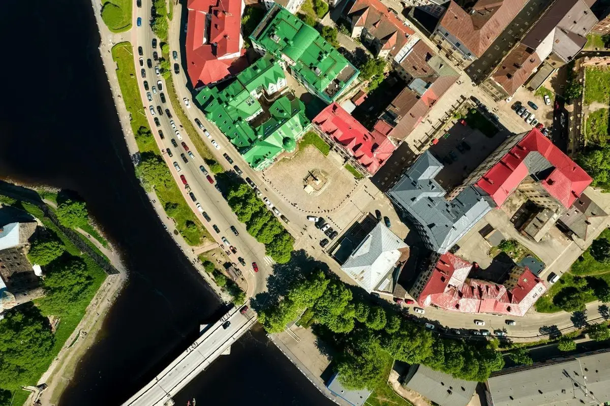 Aerial shot of a vibrant city next to a winding river, showcasing colorful rooftops and lively streets.
