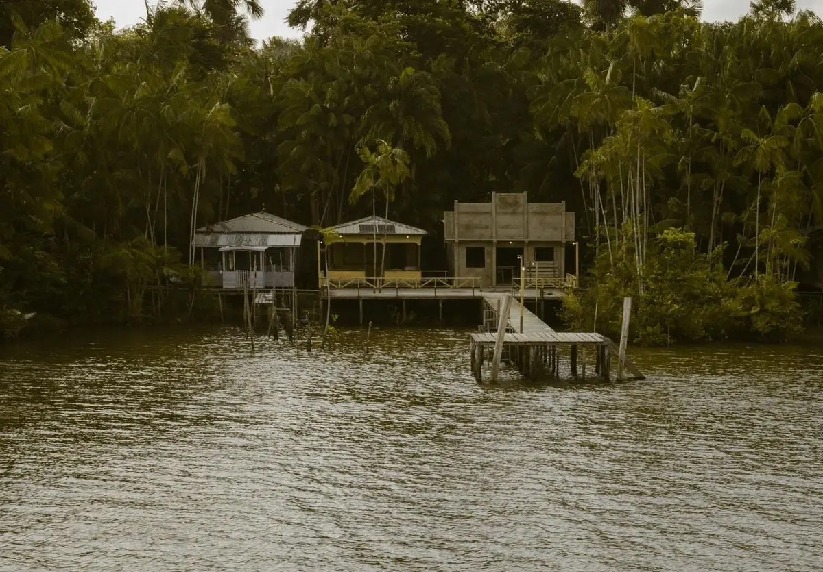 Rustic riverside houses surrounded by lush greenery in Pará, Brazil.