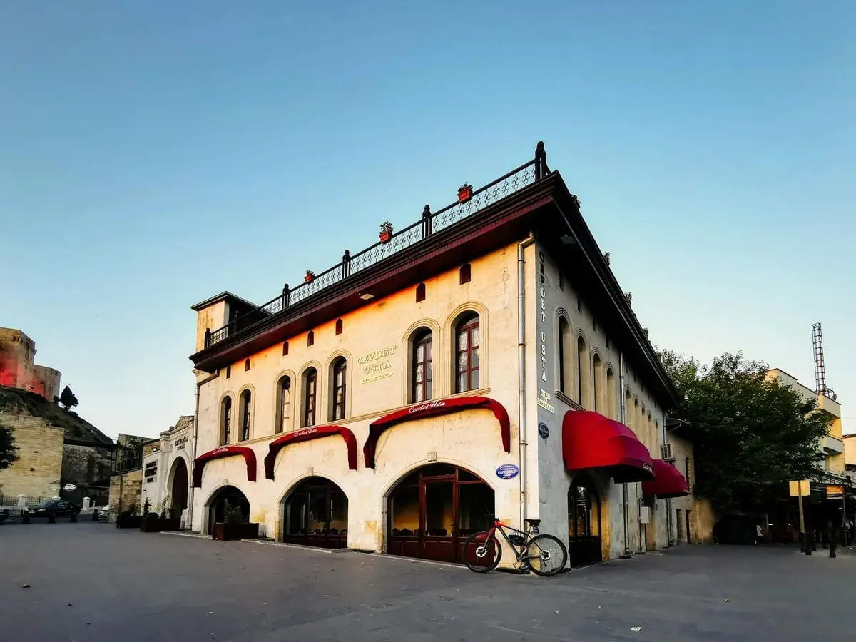 Historic building with distinct architecture and a parked bicycle under clear sky in Turkey.