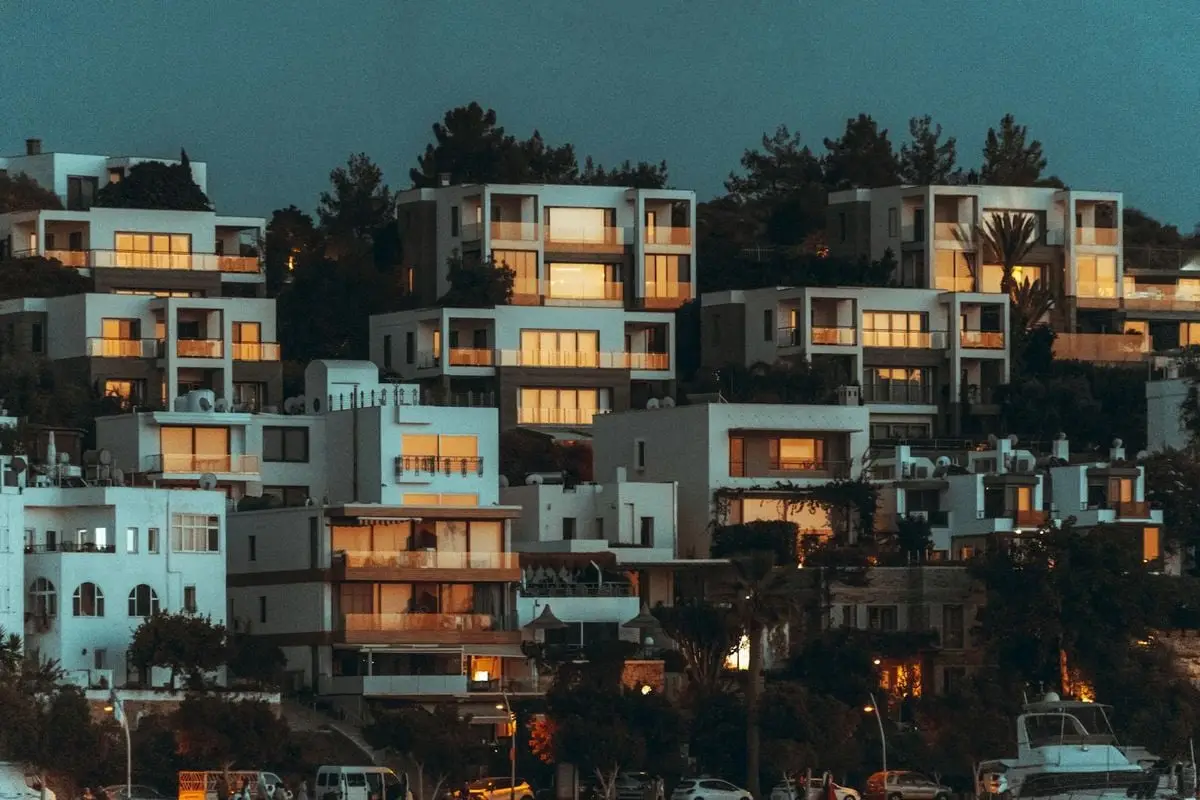Contemporary hillside houses in Bodrum, Turkey, illuminated at twilight, showcasing modern architecture.