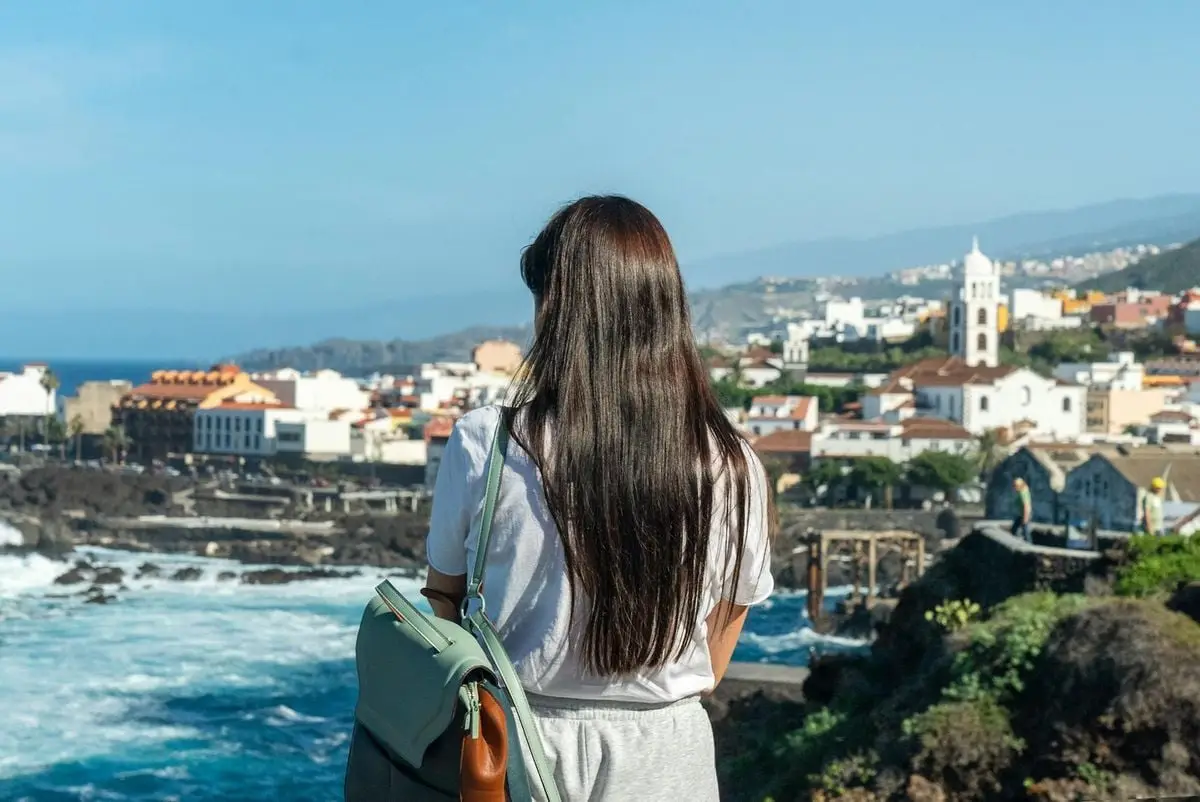 Back view of a woman overlooking the vibrant town of Garachico, Spain, with the sea in the background.