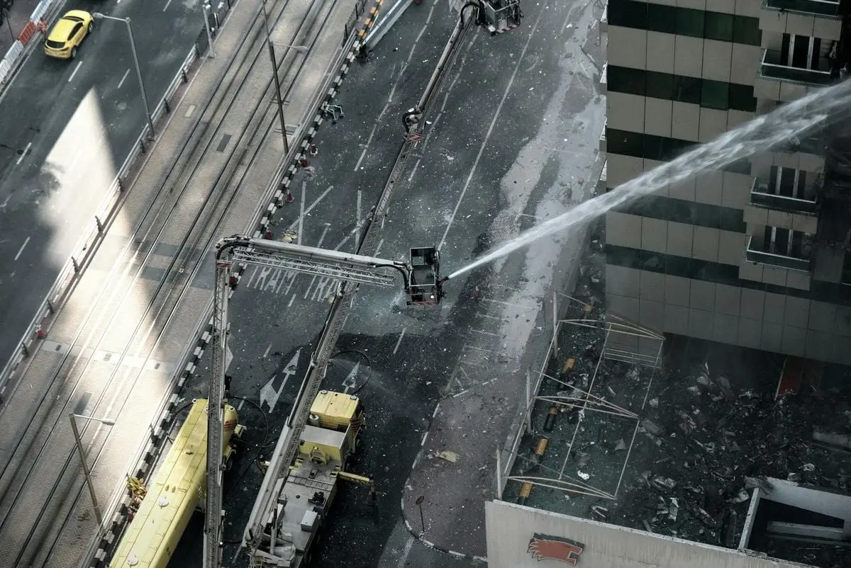 Aerial view of firefighting efforts on a high-rise building in an urban area.