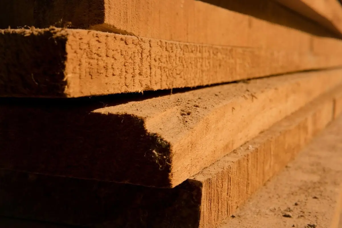 Detailed view of stacked wooden planks, highlighting texture and shadows in natural light.